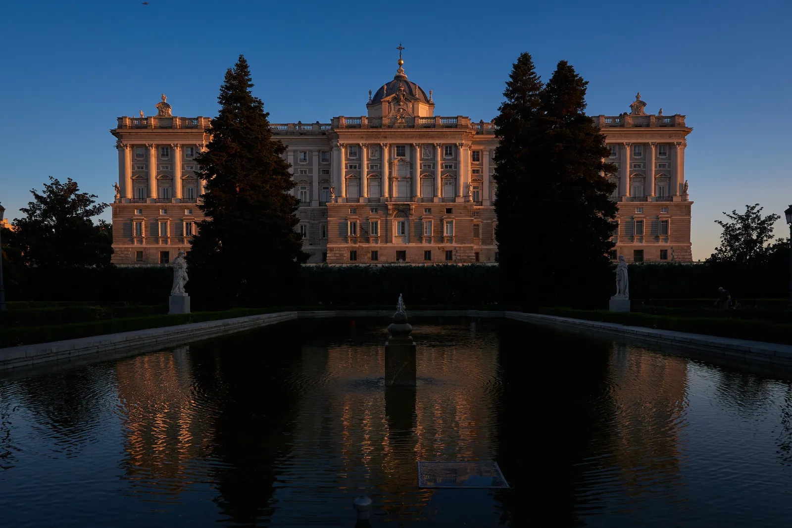 The formal hedges and fountains of the Sabatini gardens below the Royal Palace facade in Madrid, Spain