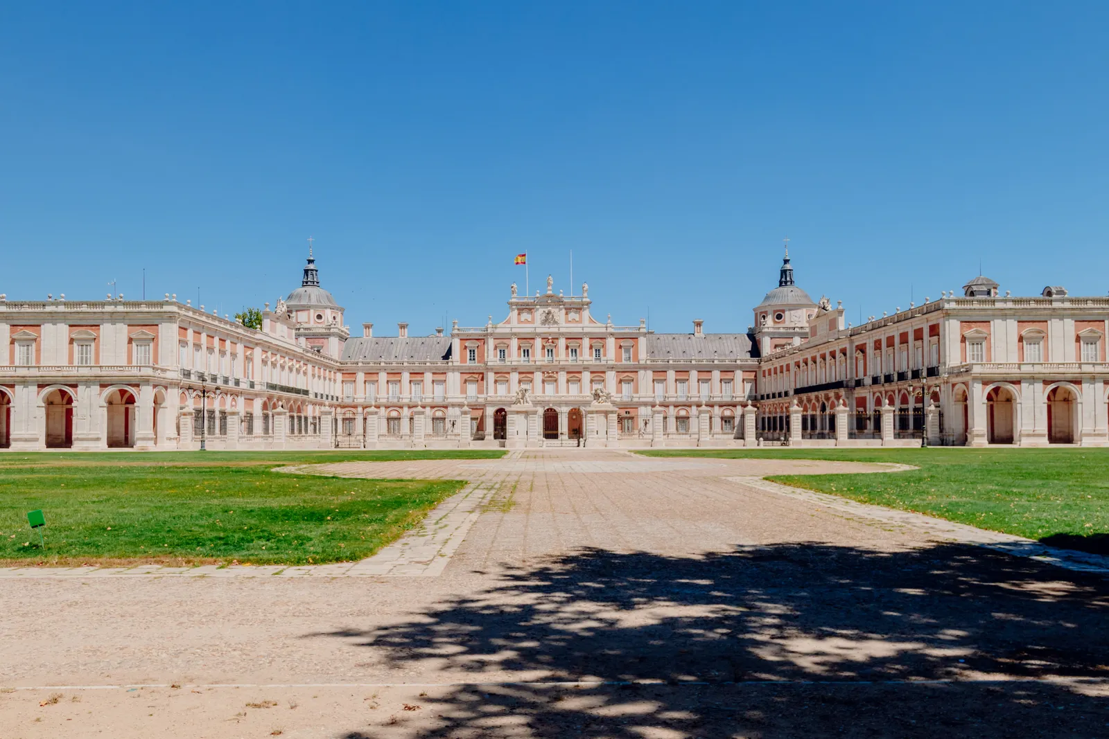 The ornate rococo facade of the Royal Palace of Aranjuez beside formal gardens in Spain