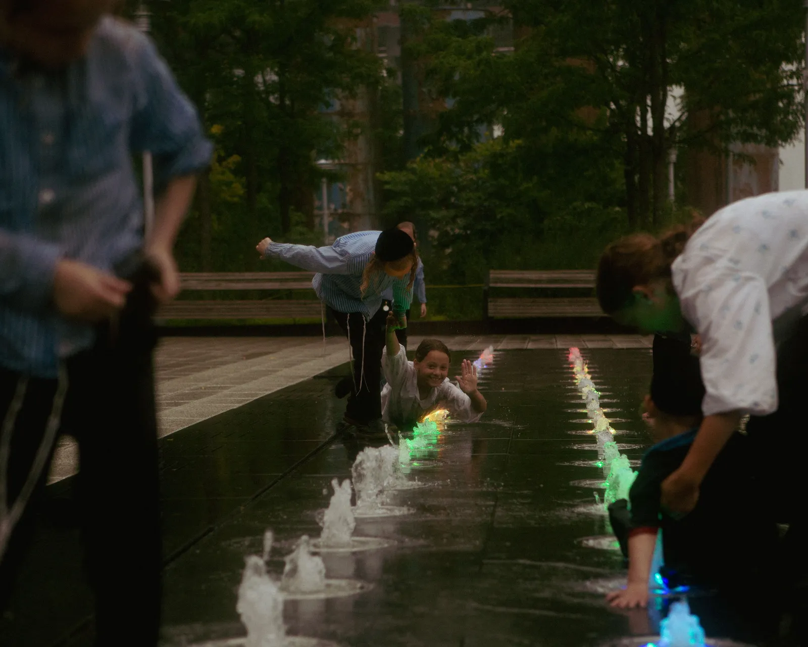 Children running through the shallow water play fountains at Madrid Rio park beside the Manzanares river, Spain