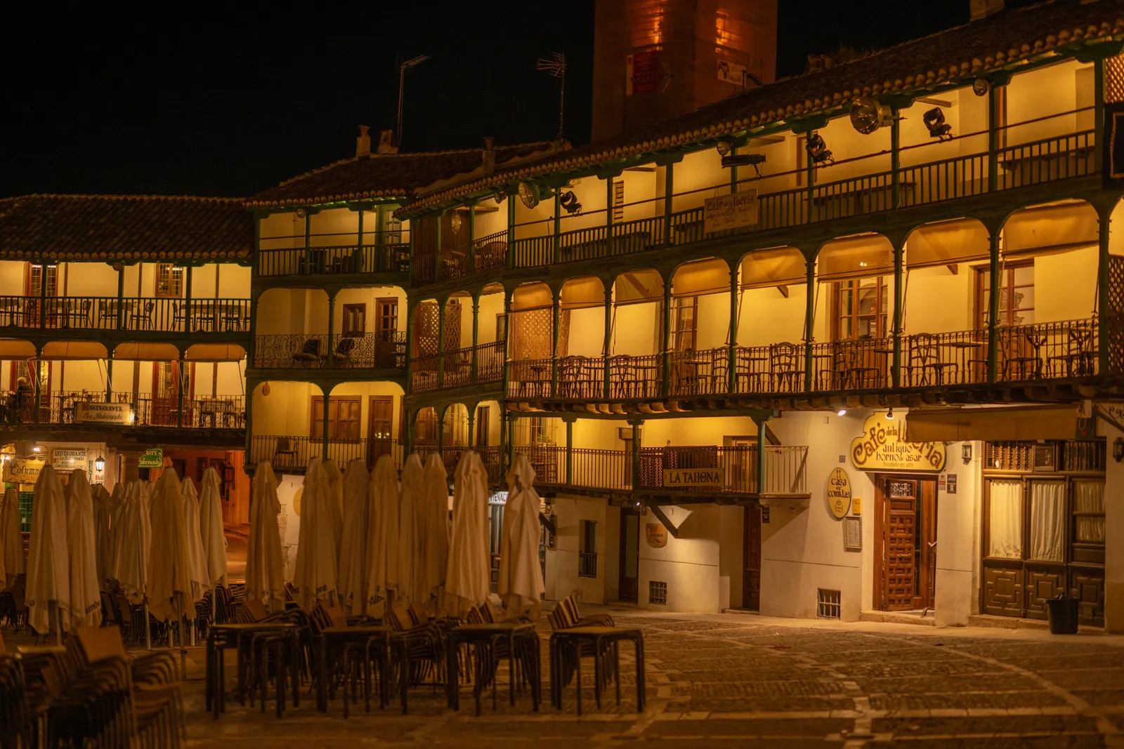 A traditional Castilian restaurant terrace with wooden tables under the arcaded balconies of Chinchon's main square, Spain