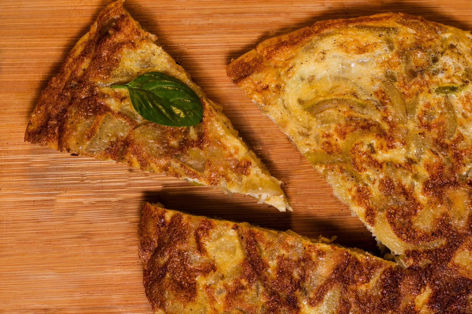 A slice of Spanish potato omelette served on a wooden board in Madrid, Spain