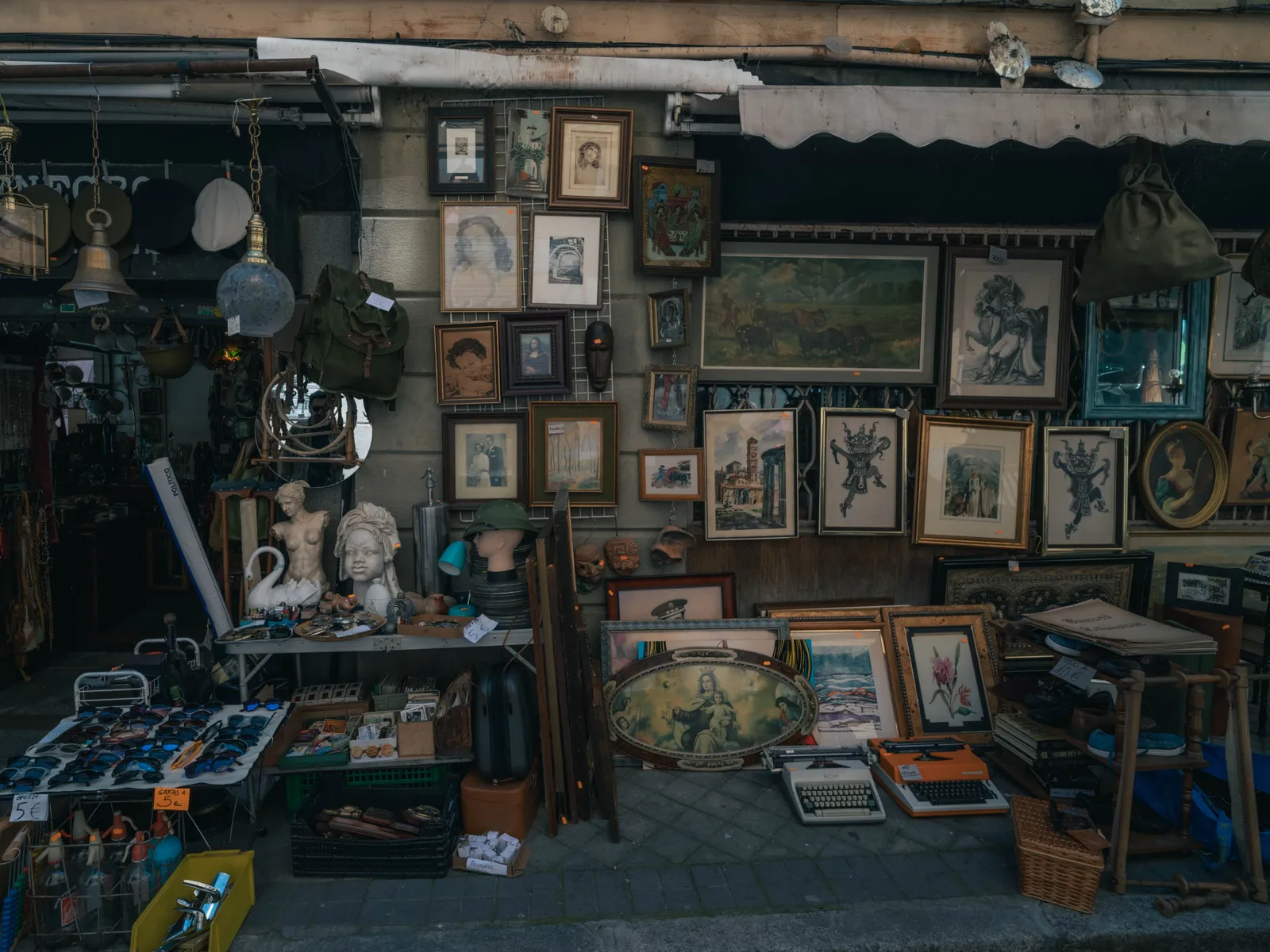 An antiques stall hung with paintings and frames at El Rastro market in Madrid, Spain