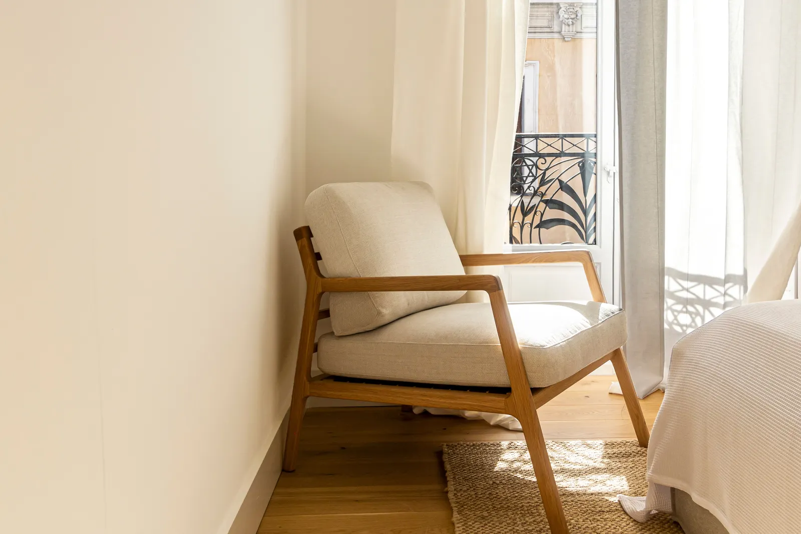 A sunlit hotel room with a chair beside a balcony window in Madrid, Spain