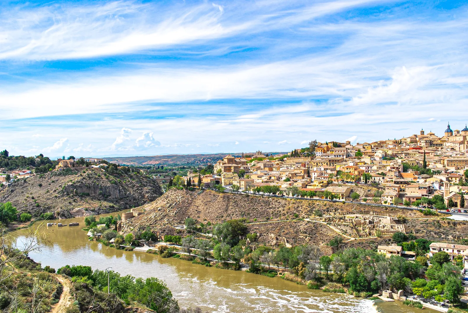 The medieval skyline of Toledo rising above a river on a clear day near Madrid