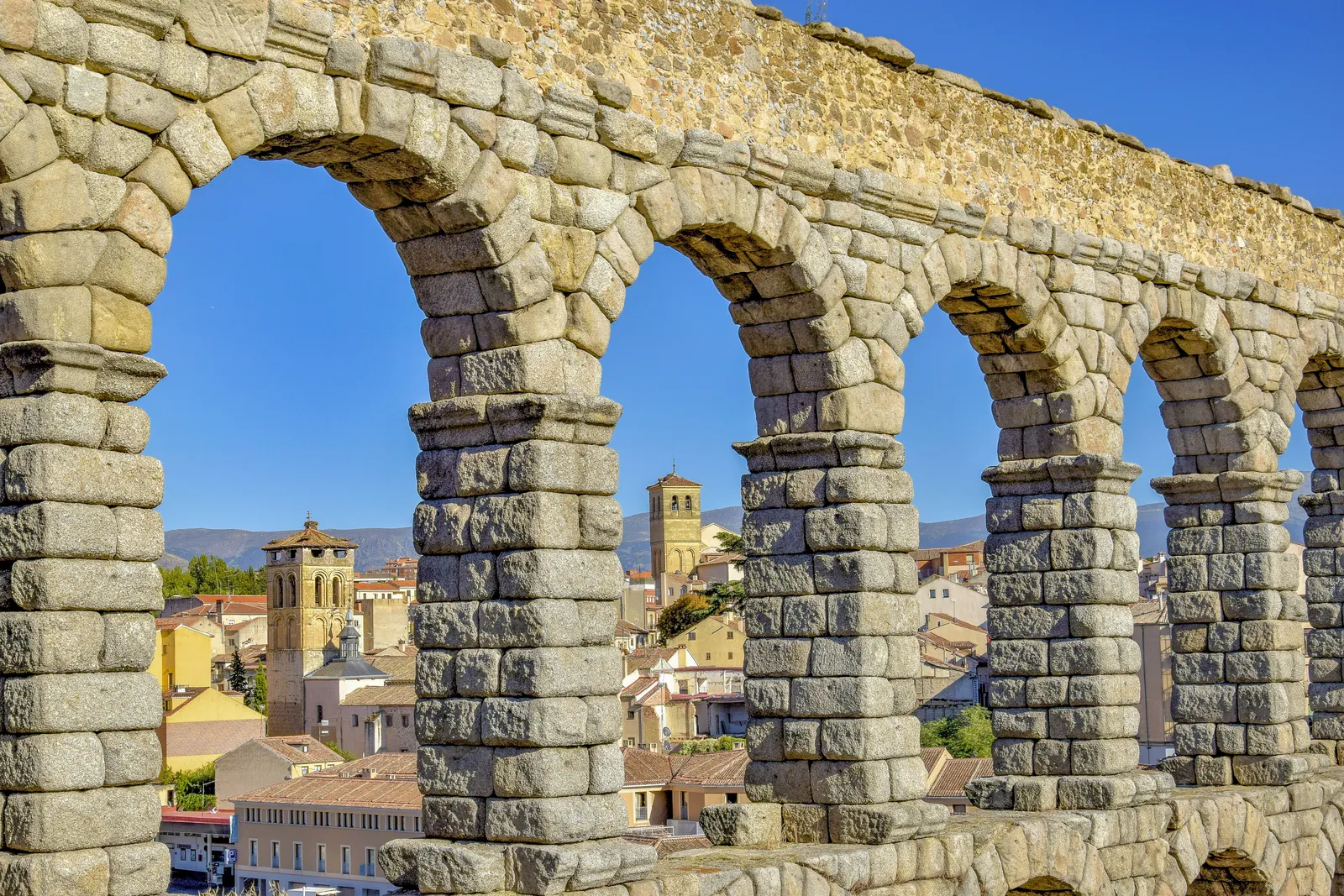 The Roman aqueduct of Segovia towering over the town square on a sunny day