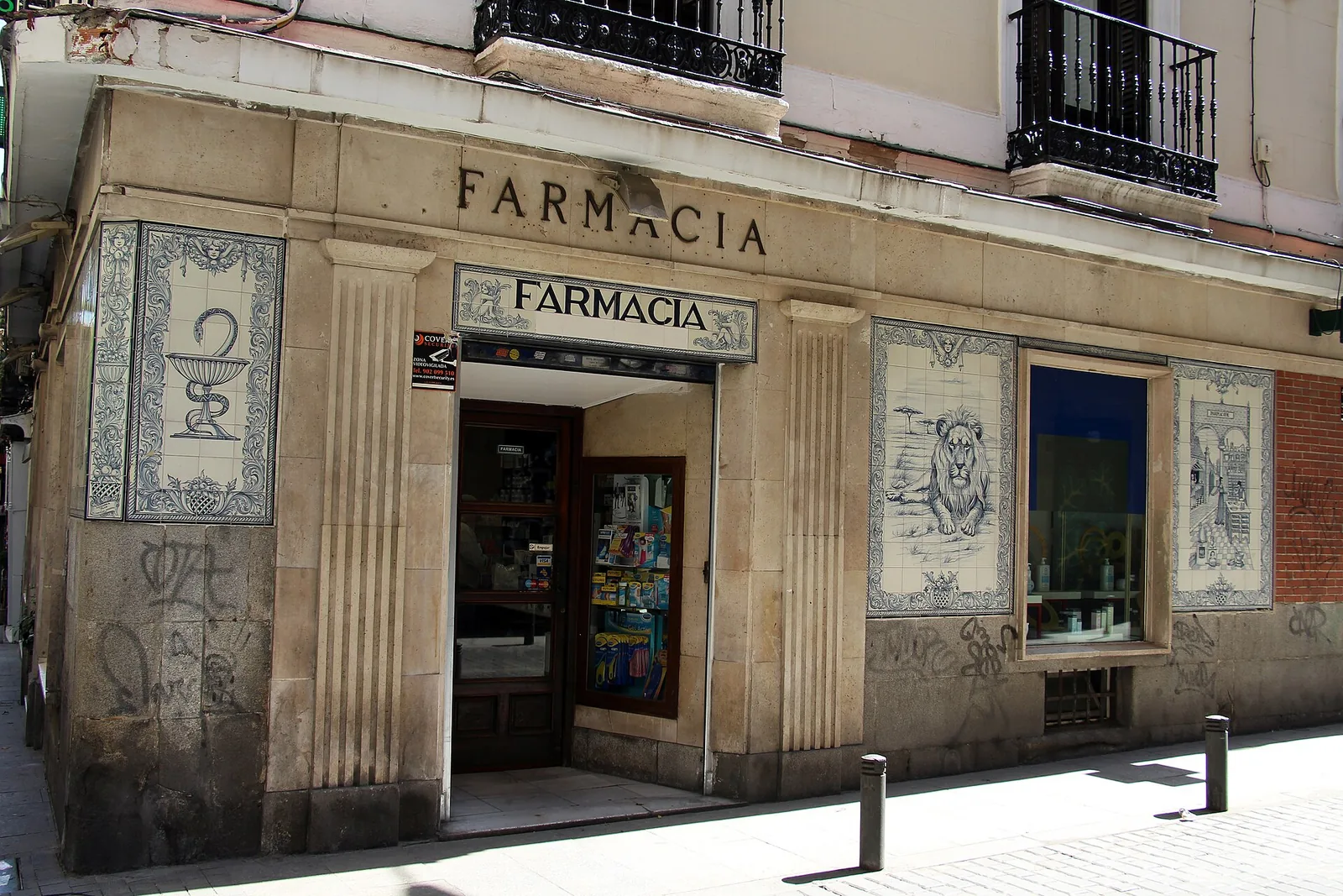 The tiled facade of a traditional pharmacy on a street corner in Madrid, Spain
