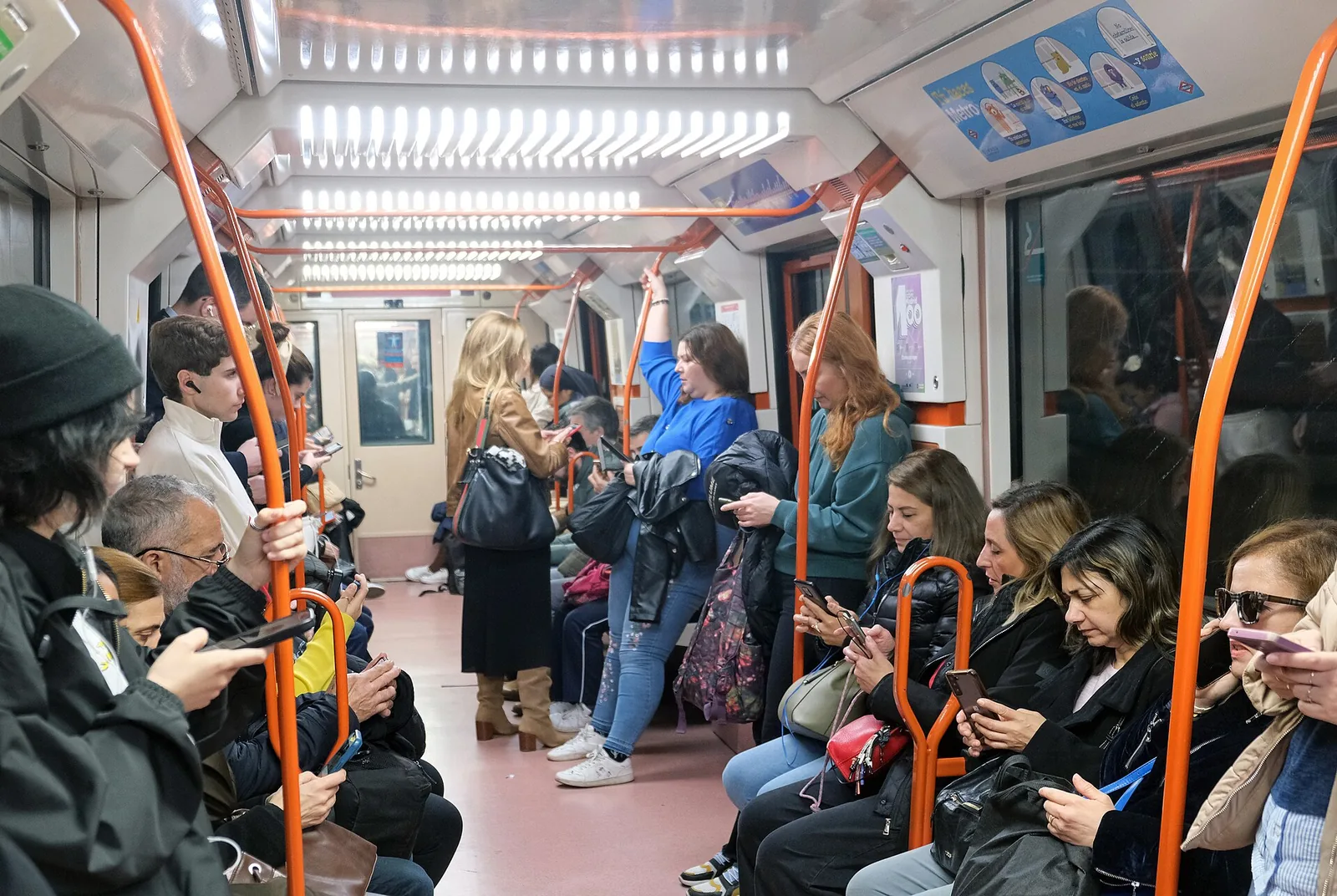 Passengers standing in a full Madrid metro carriage looking at their phones, Spain