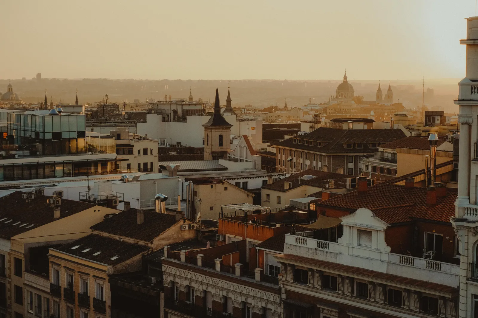 The rooftops of central Madrid at dusk with church spires above the tiles