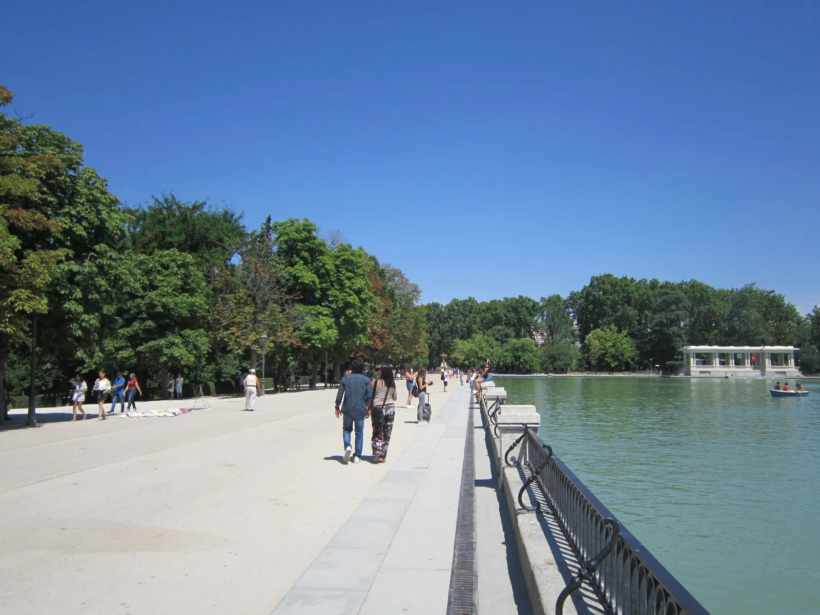 People walking along the lakeside promenade in the Retiro park in summer, Madrid, Spain