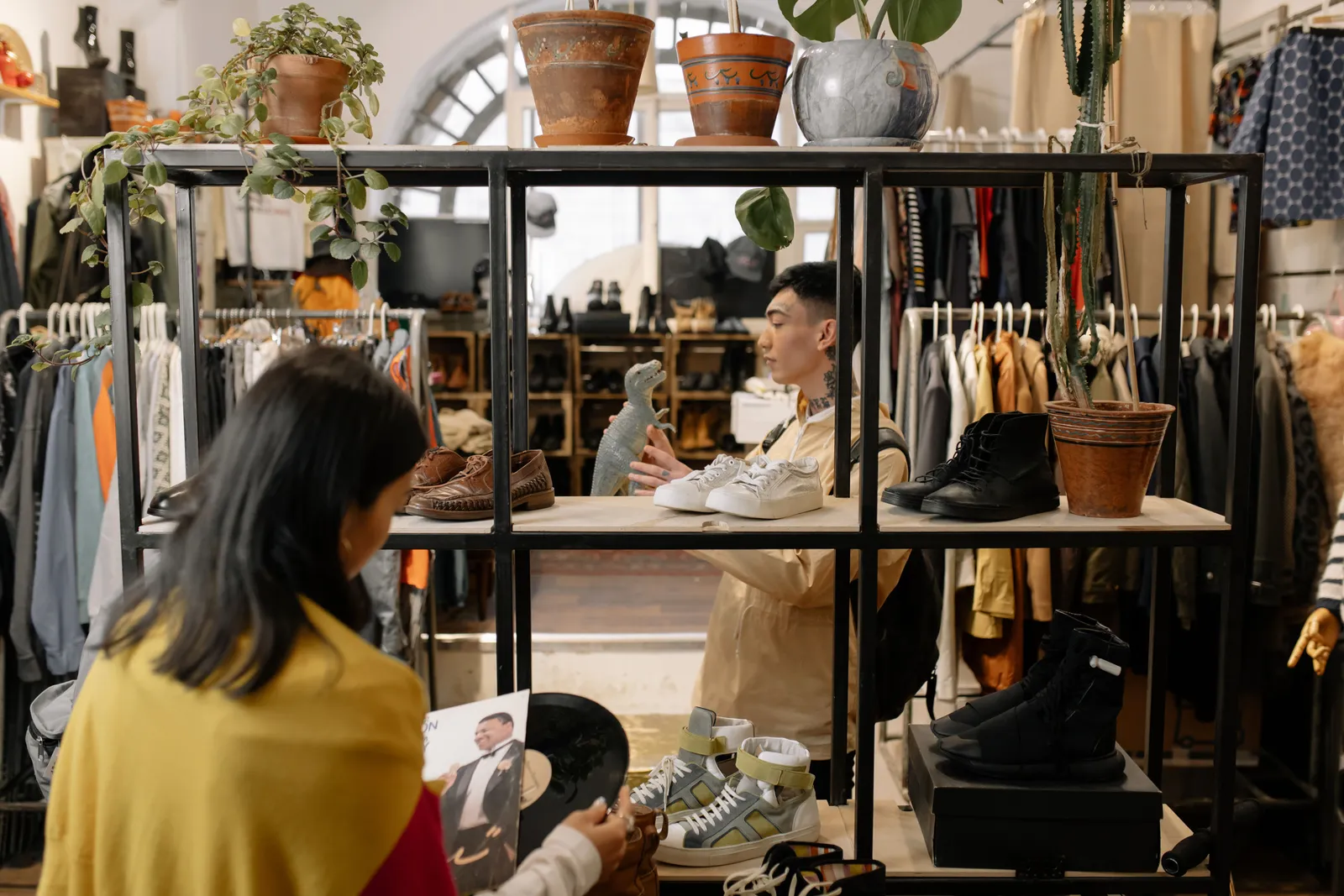 Shoppers browsing shoes, records and clothing on shelves inside a vintage shop
