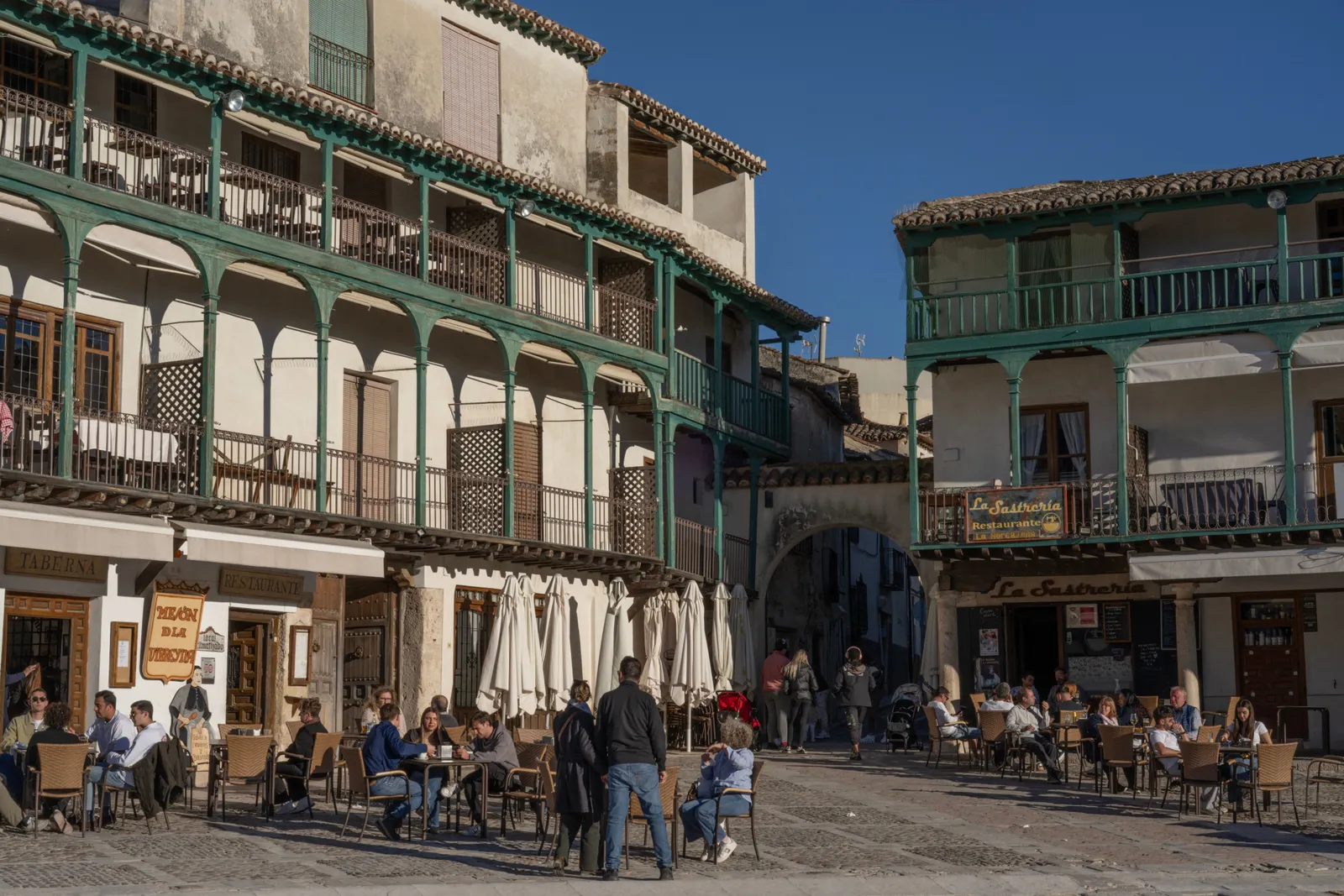 A historic arcaded square with wooden balconies and cafe terraces in the Madrid region in daylight
