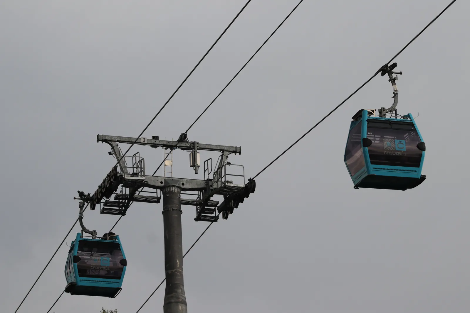 A cable car cabin crossing above the woodland of Casa de Campo with the Madrid skyline behind, Spain