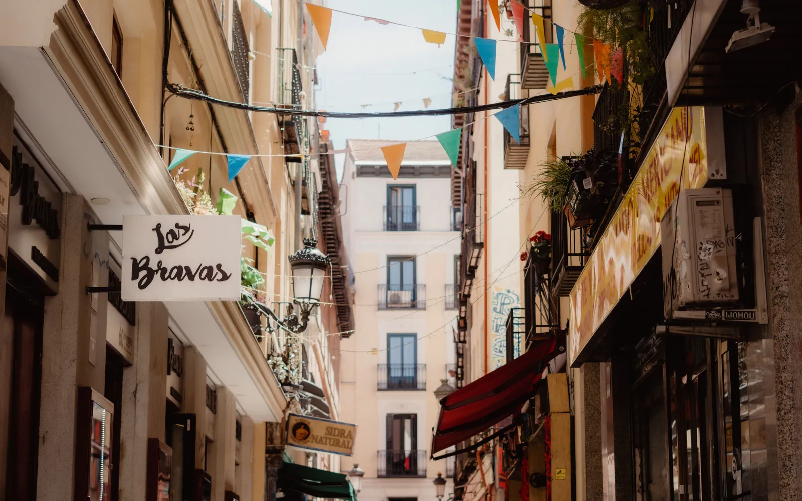 A narrow street hung with bunting in the Malasana district of Madrid, Spain