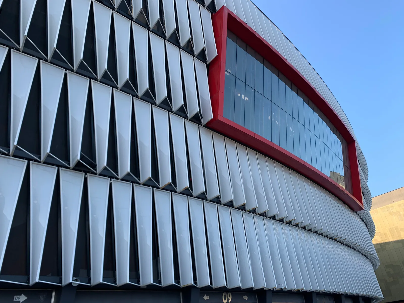 The red and white exterior facade of a football stadium in Spain in daylight