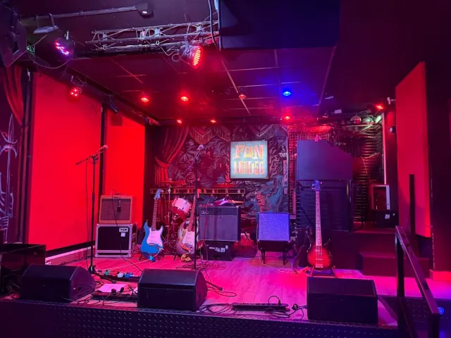 An empty stage with guitars, amplifiers and speakers in red lighting