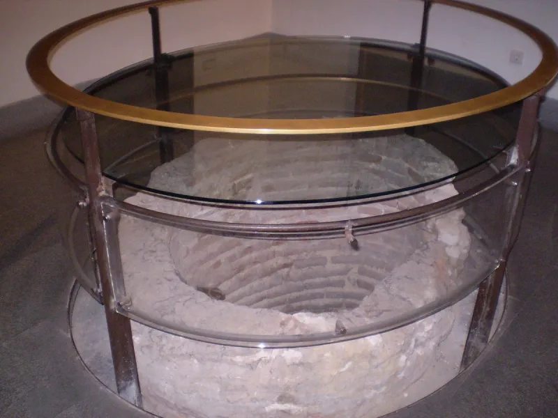 An ancient stone well under a glass cover inside the exhibition hall of the Museo de San Isidro
