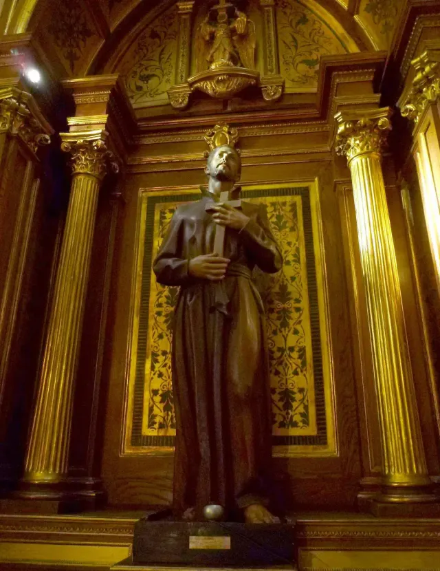 A gilded statue of a robed saint set in a golden decorated niche inside the church