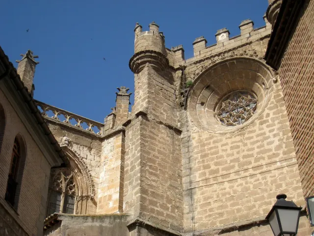 A massive Gothic stone facade with a round rose window and arched openings in daylight