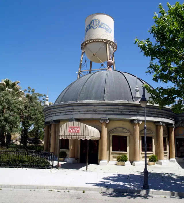 A round building with a dark dome and a branded water tower above it against a blue sky