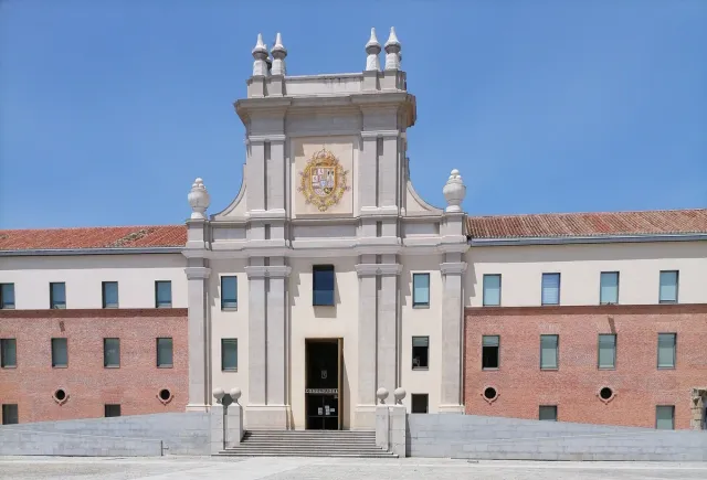 A long pale brick Baroque facade with an ornate stone portal at its centre