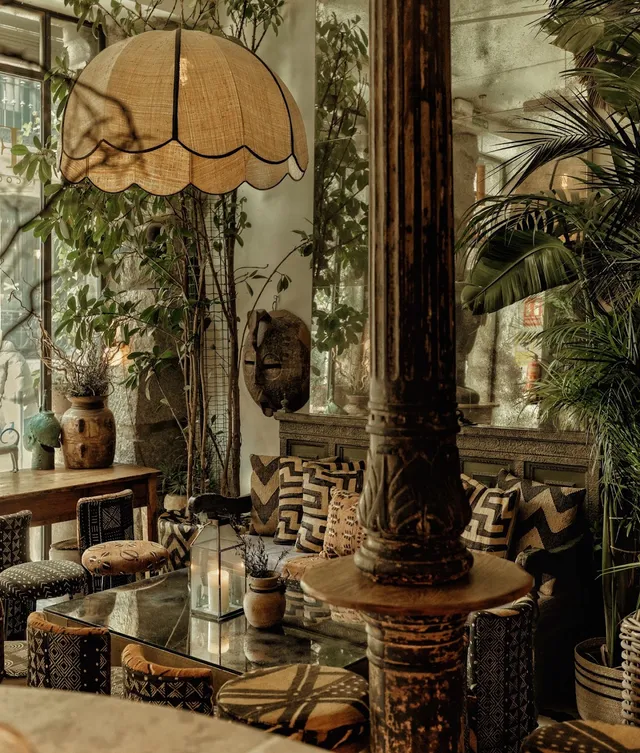 A seating corner with patterned cushions, a large straw lamp and green potted plants