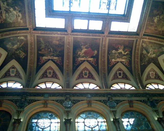 A painted vaulted ceiling with coloured stained glass and decorated arches