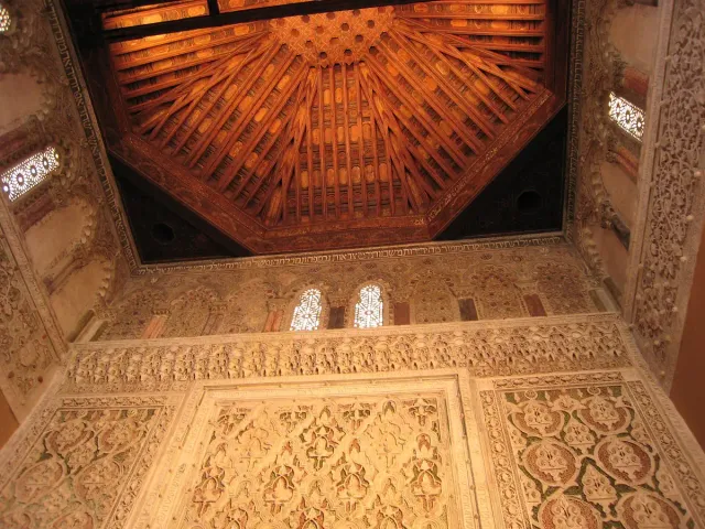 A decorated wooden ceiling and carved plaster walls in geometric Mudejar patterns