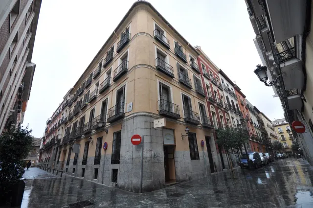 A narrow old town street lined with stone buildings and iron balconies on both sides