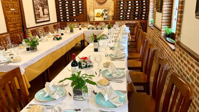 Long tables laid with white cloths and green plates, in a room with brick walls