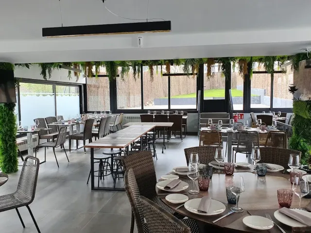 A bright dining room with greenery garlands on the ceiling, large windows and laid tables