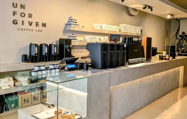 A long concrete counter with coffee machines, grinders and metal letters on the wall