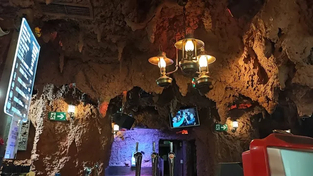 A cave-style ceiling with stalactites and hanging lantern lamps in warm light