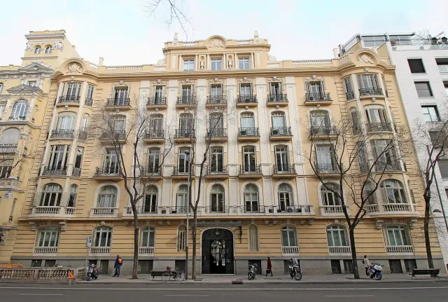 The sand coloured facade of a historic apartment building with rows of ornate iron balconies