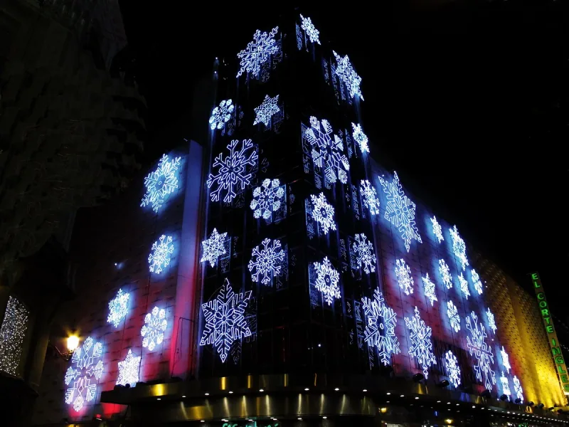 A tall department store facade covered in white and blue snowflake lights at night with the El Corte Ingles sign at its edge
