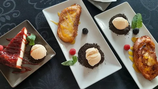 Three dessert plates with scoops of ice cream, cheesecake in red sauce and berries