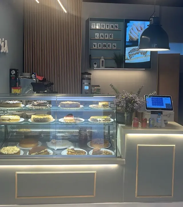 A lit display case holding whole and sliced cakes on two shelf levels