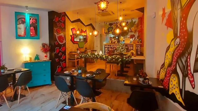 A colourful restaurant interior with wall murals, hanging lamps and dark tables
