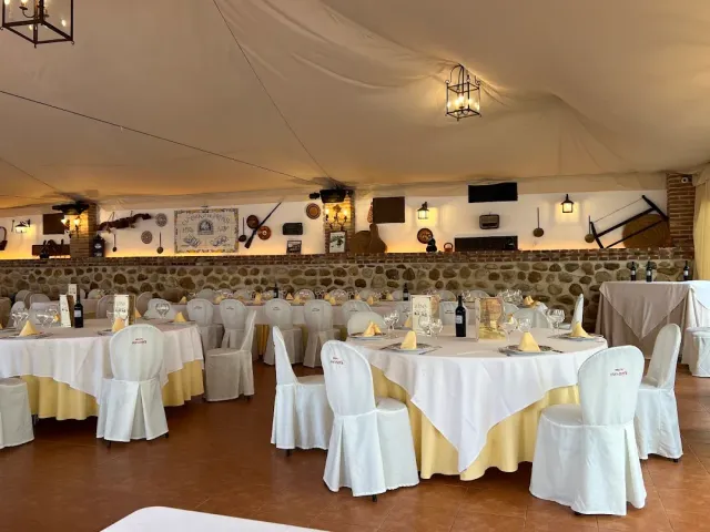 An event hall under a canvas roof with round tables and white chair covers