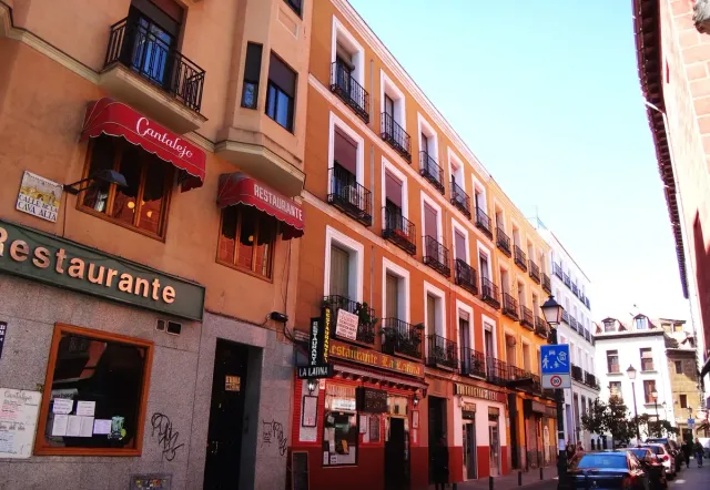 A narrow street with terracotta and orange house fronts and restaurant and bar signs