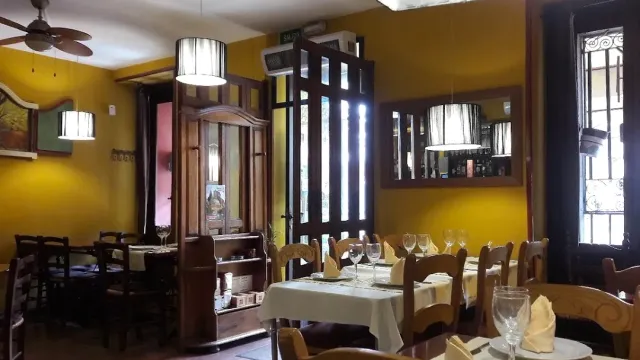 A dining room with yellow walls, wooden partitions, hanging lamps and laid tables