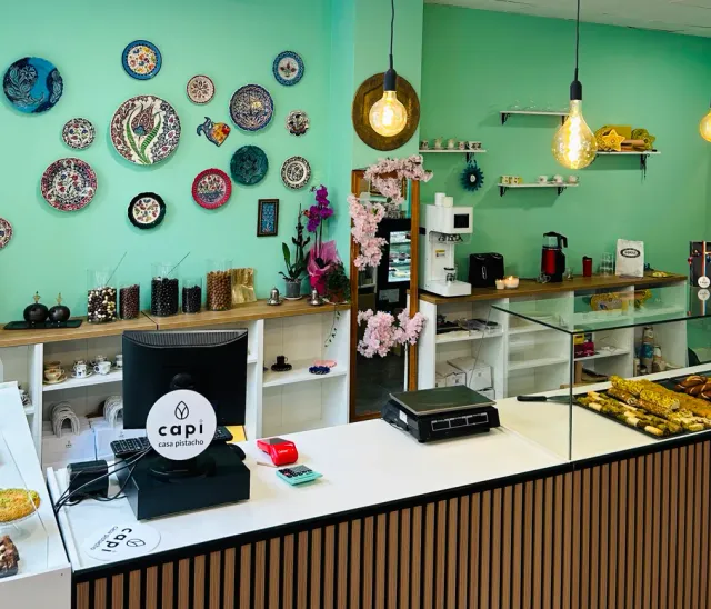 A mint green wall with painted ceramic plates above a counter and a pastry case