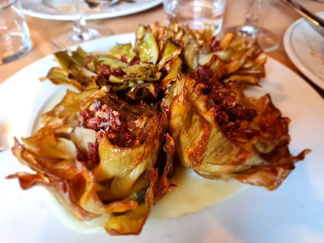 Fried artichokes opened like flowers with sausage crumbs over a pale sauce