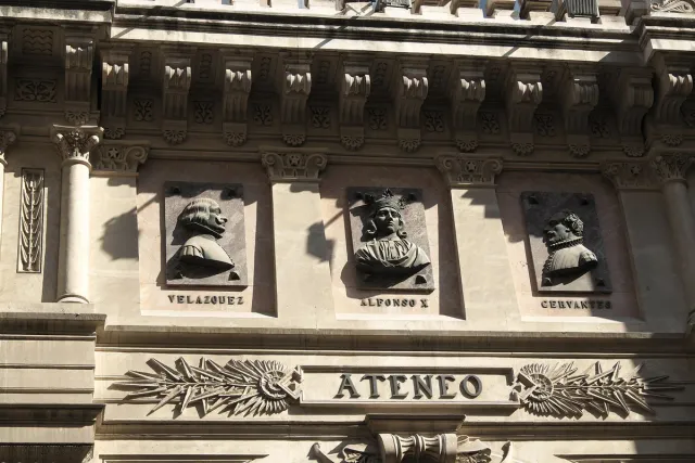 A carved stone facade with portrait medallions and raised lettering above the entrance
