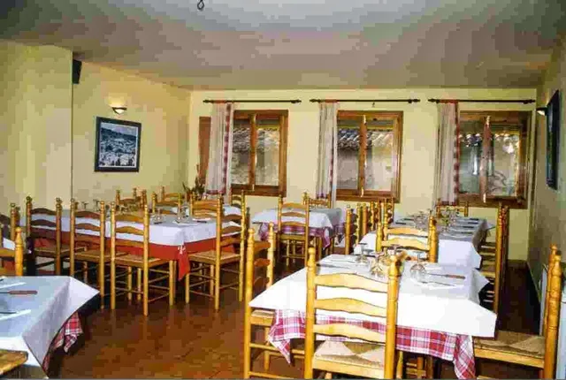A rustic dining room with woven wooden chairs and red and white checked tablecloths