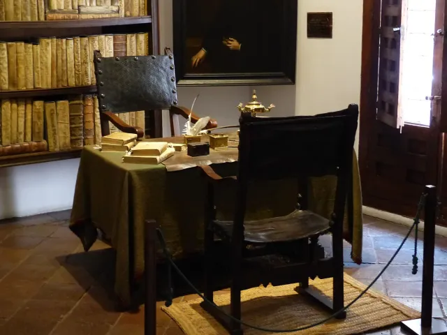 A seventeenth century study with a writing desk, wooden chair and shelves of old books