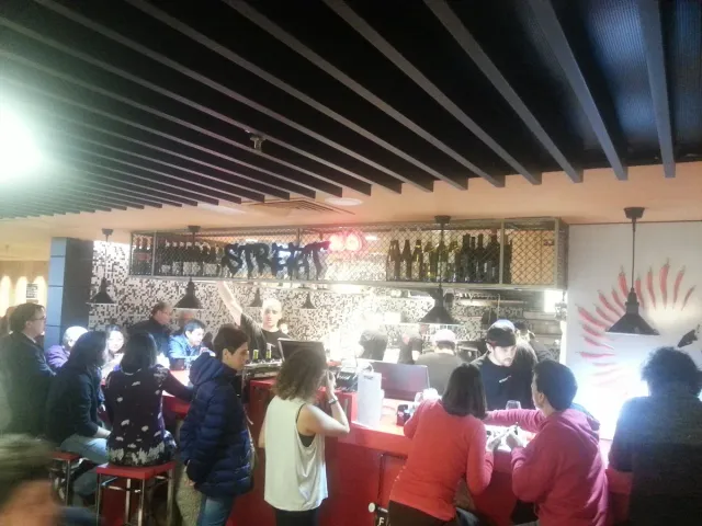 A busy restaurant space with an open counter facing the kitchen, seated guests and warm lighting