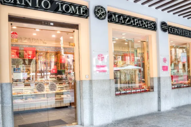 A sweet shop front with black signs above the display windows and pastries in the case