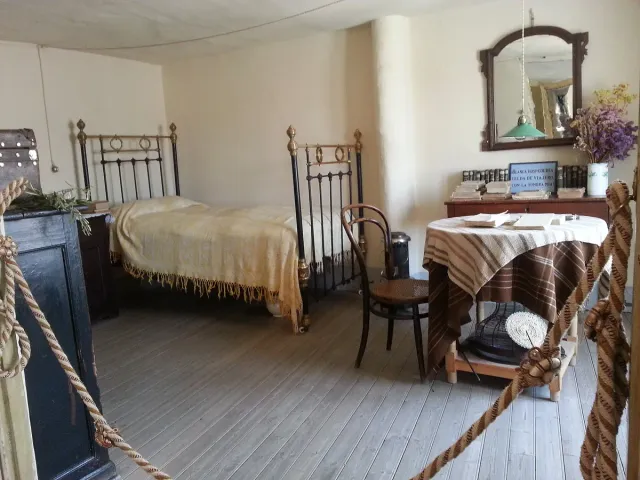 A modest bedroom with an iron bed, a round table and a mirror on the wall