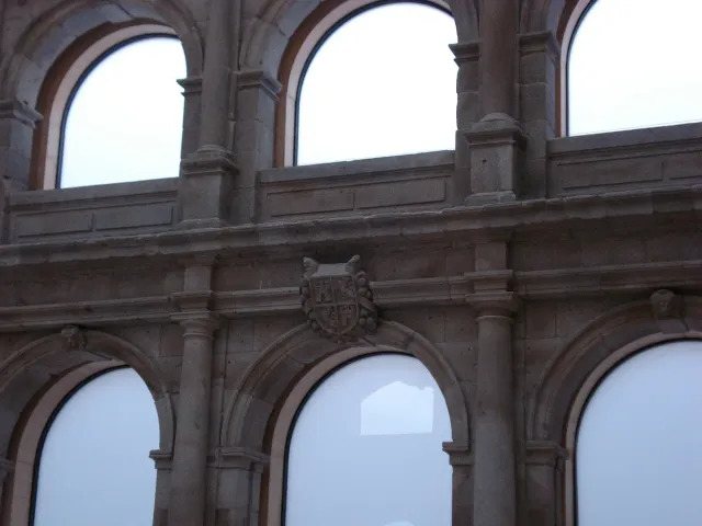 A row of white stone cloister arches with tall windows above them
