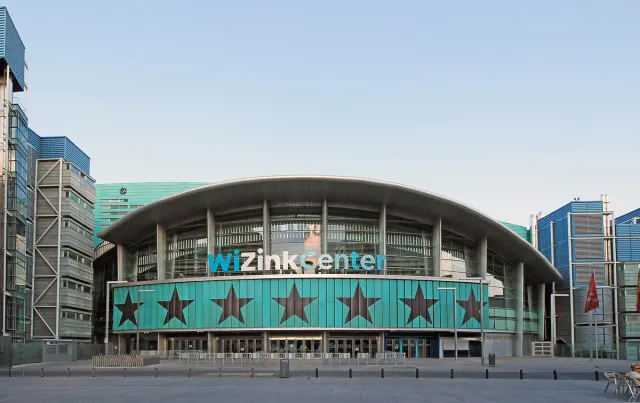 A large arena with a curved roof and a glass front, with a star sign on the wall